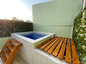 Un bain à remous avec un banc en bois et une échelle en bois.