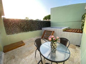 A patio with a glass table and chairs, a wooden bench, and a wall with a textured pattern. - Beautiful 3 Bedroom Old City House (Cartagena de Indias)