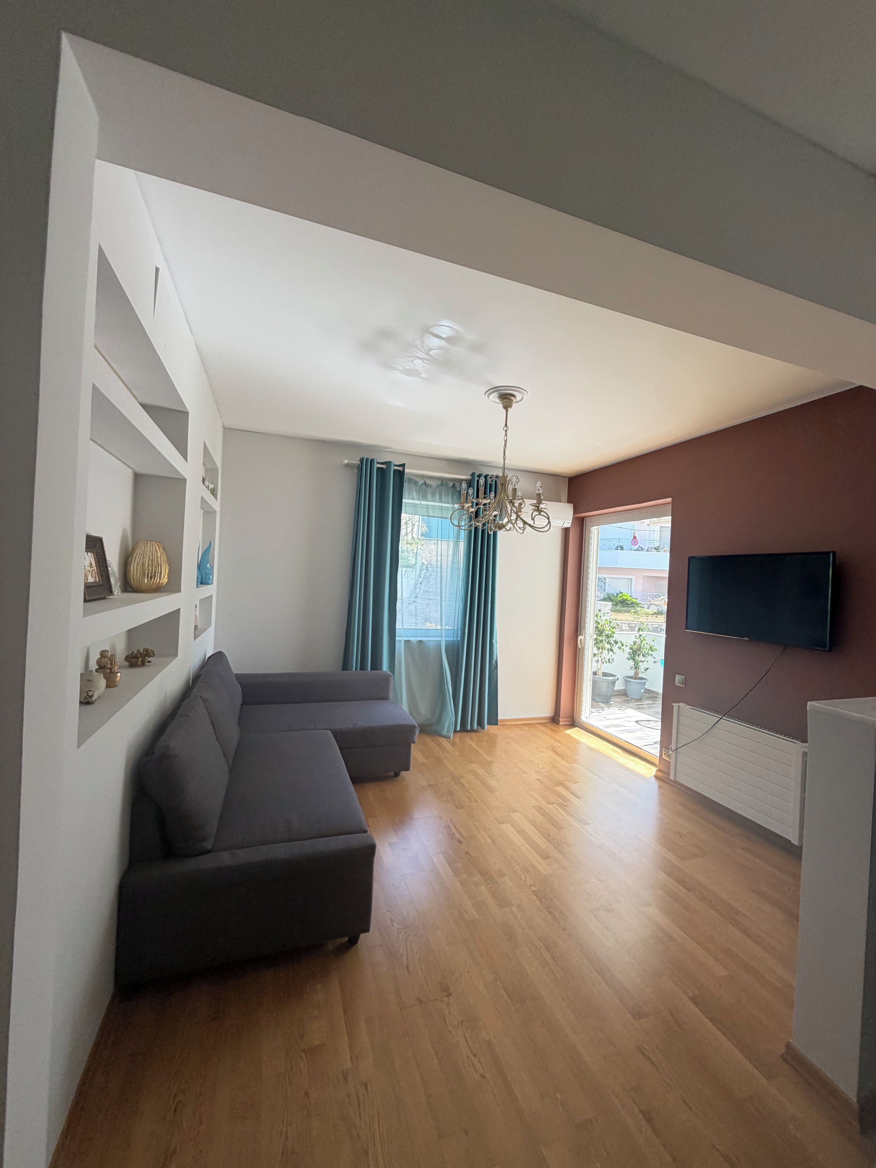 A modern living room with a sectional sofa, a flat-screen TV, and a ceiling fan.