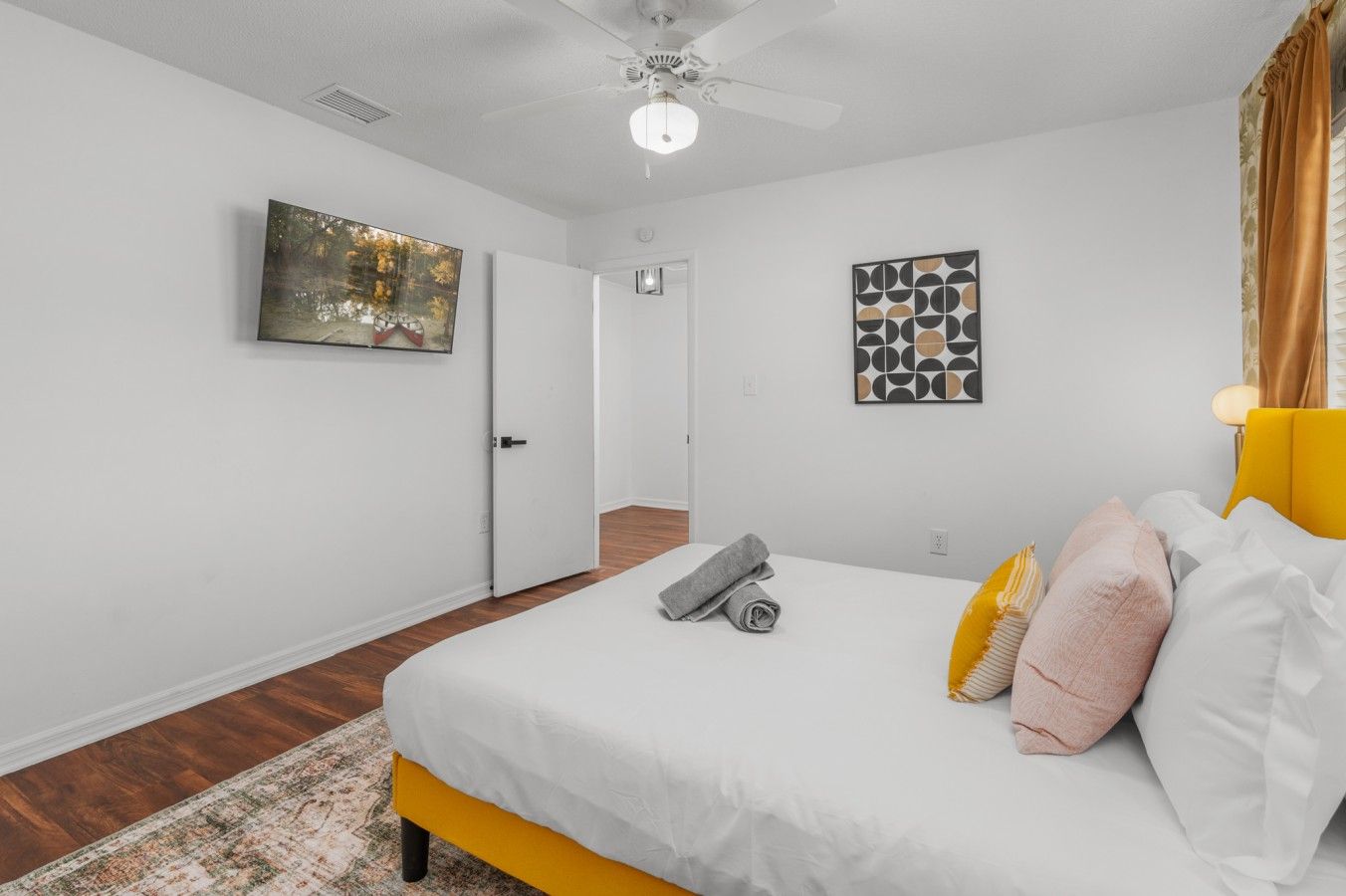 A bedroom with a bed, a ceiling fan, a door, and a rug.