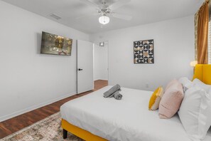 A bedroom with a bed, a ceiling fan, a door, and a rug.