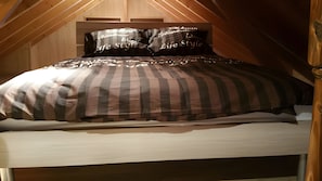 Een bed in een kamer met houten wanden en schuine plafonds.