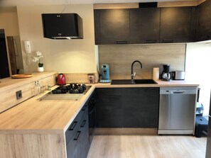 A modern kitchen with a built-in dishwasher, a gas stove, and a coffee maker. - New Listing (Remiremont)