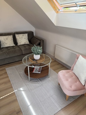 Ein modernes Wohnzimmer mit einer Couch, einem Couchtisch und einem rosa Sessel.