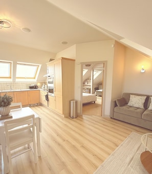Eine moderne Küche mit Holzschränken, einem Esstisch und Blick auf das angrenzende Schlafzimmer.