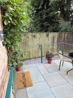 A patio with a wooden fence, a bench, potted plants, and a welcome mat. - 1 Bedroom Private Meadow View Annexe Apartment (Allington)