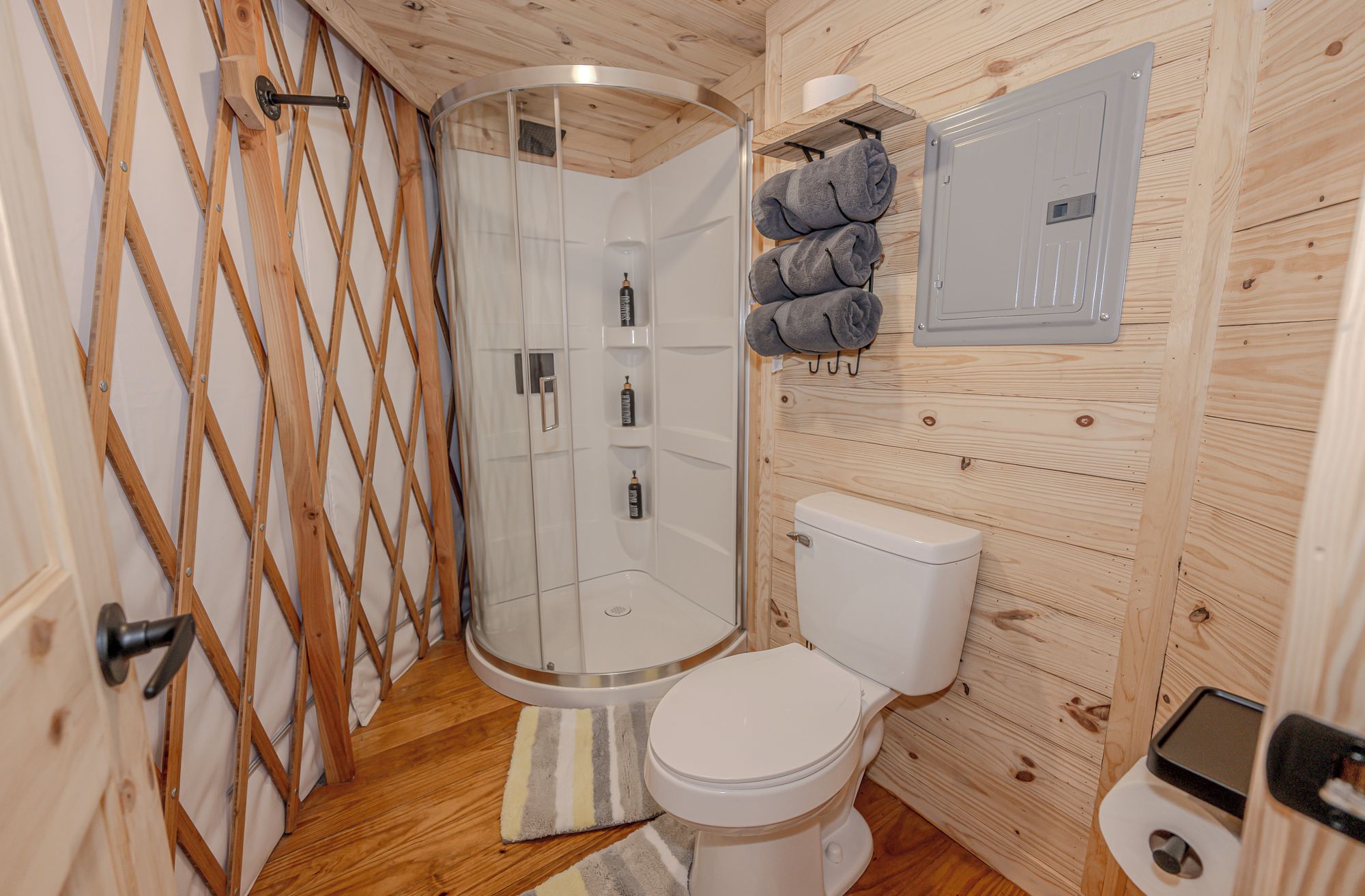 A compact bathroom with a shower enclosure, toilet, and a towel rack.