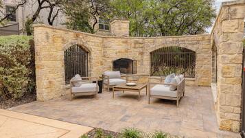 Un patio de piedra con mobiliario exterior, una chimenea y un muro de piedra.