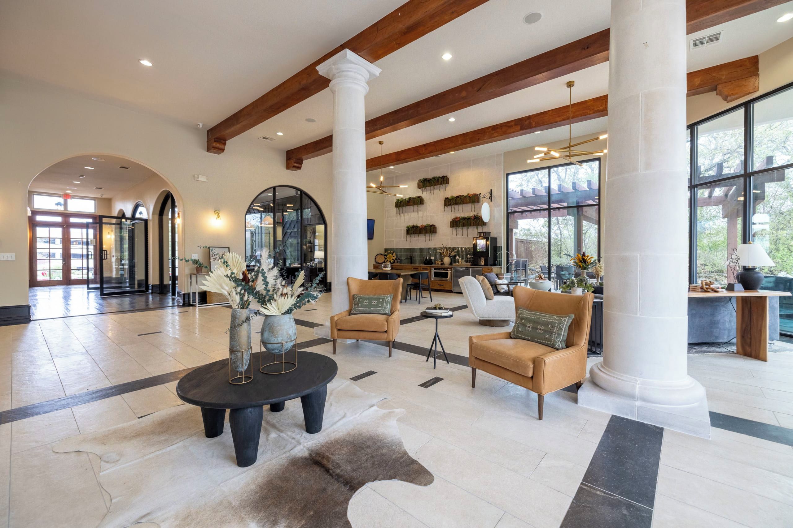Eine geräumige Lobby mit hohen Decken, großen Fenstern und einer zentralen Sitzecke mit Sofas und einem Couchtisch.