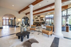 Eine geräumige Lobby mit hohen Decken, großen Fenstern und einer zentralen Sitzecke mit Sofas und einem Couchtisch.