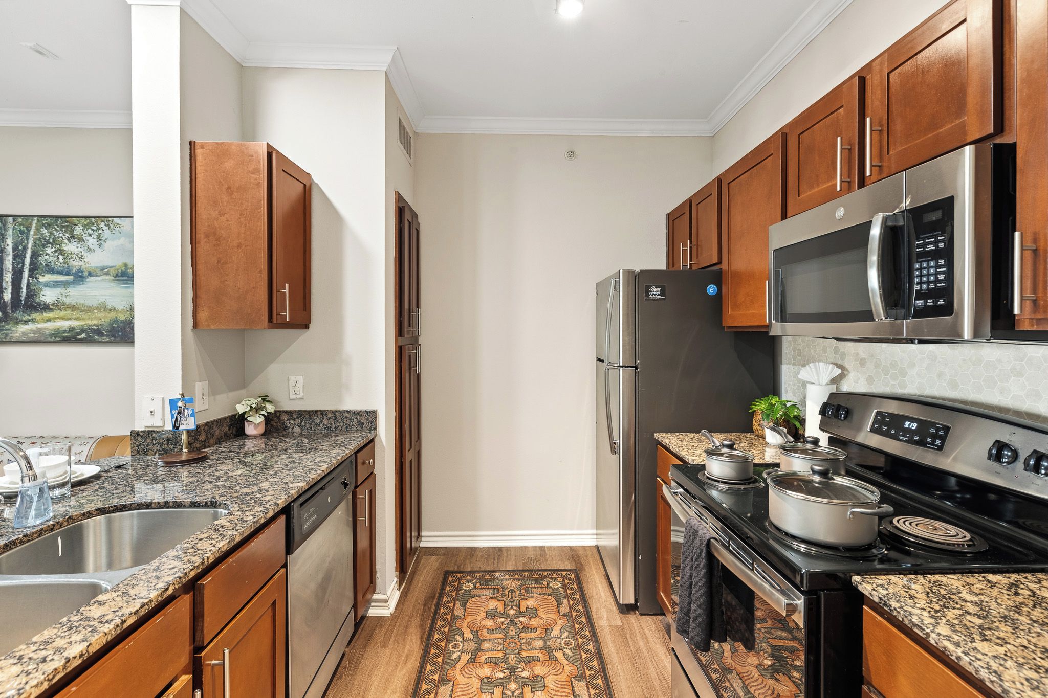 A modern kitchen with granite countertops, stainless steel appliances, and wooden cabinets.