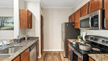 A modern kitchen with granite countertops, stainless steel appliances, and wooden cabinets.