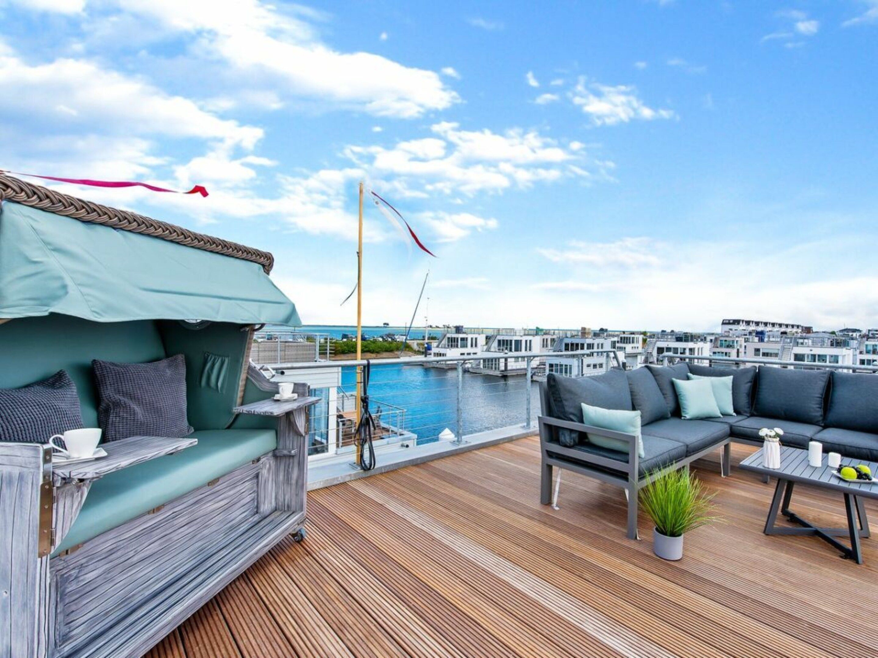 A rooftop terrace with a view of a marina, a pool, and modern buildings in the background.