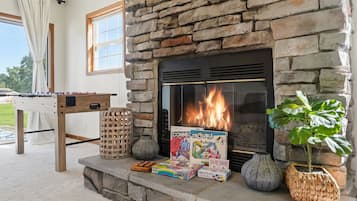 A stone fireplace with a fire, surrounded by various board games and a plant.
