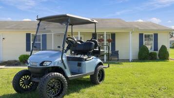 A golf cart parked in front of a house with a garage.