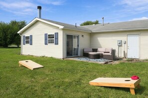 Ein Haus mit überdachter Terrasse, einer Schiebetür und einer kleinen Sitzgelegenheit im Freien.