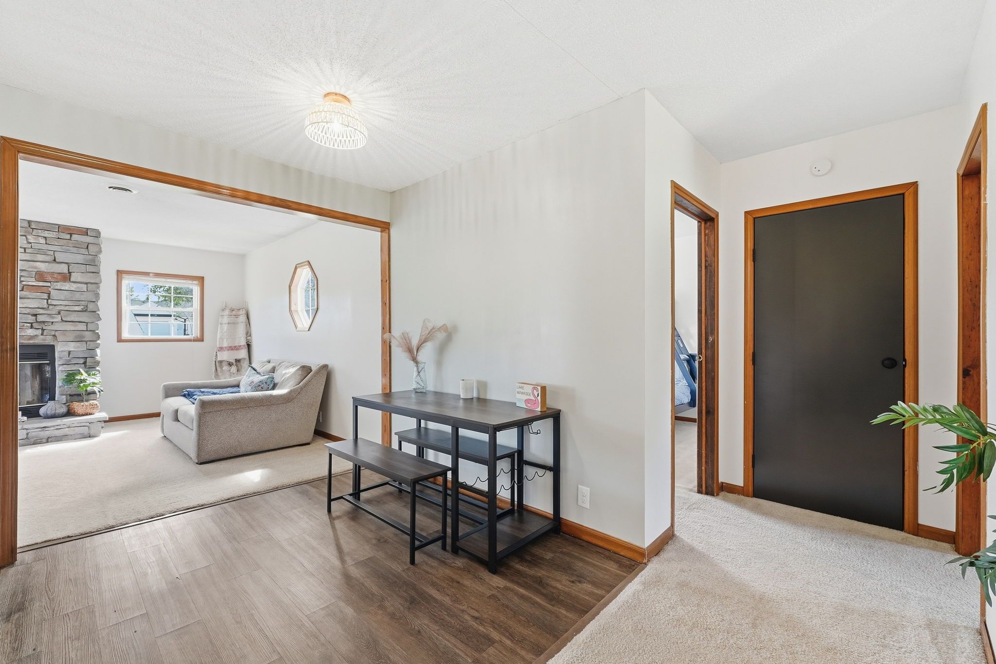Un vaste espace de vie comprenant une cheminée, un canapé, une table à manger avec des chaises et un couloir menant à une porte.