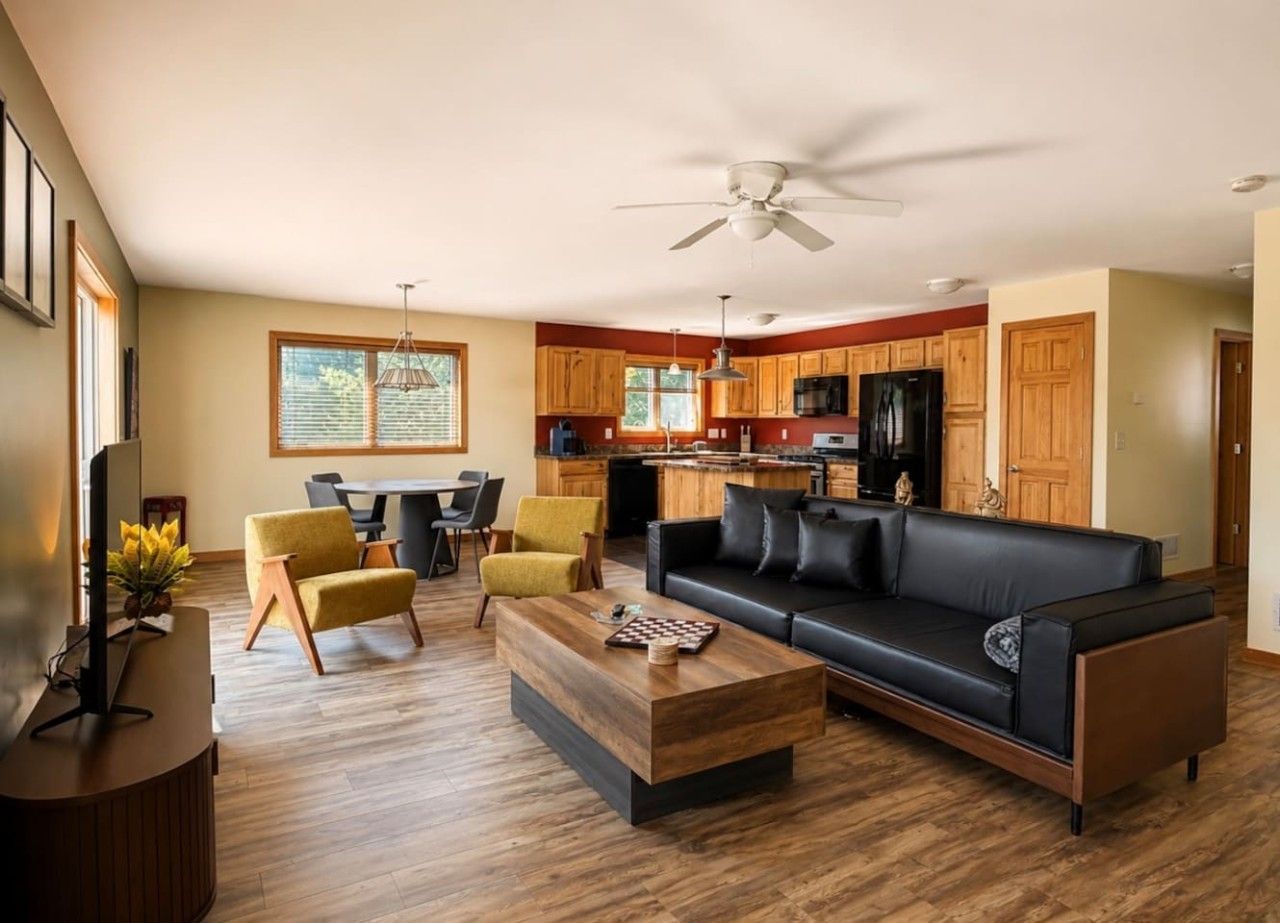 A modern living room with a black sofa, wooden coffee table, and yellow armchairs.