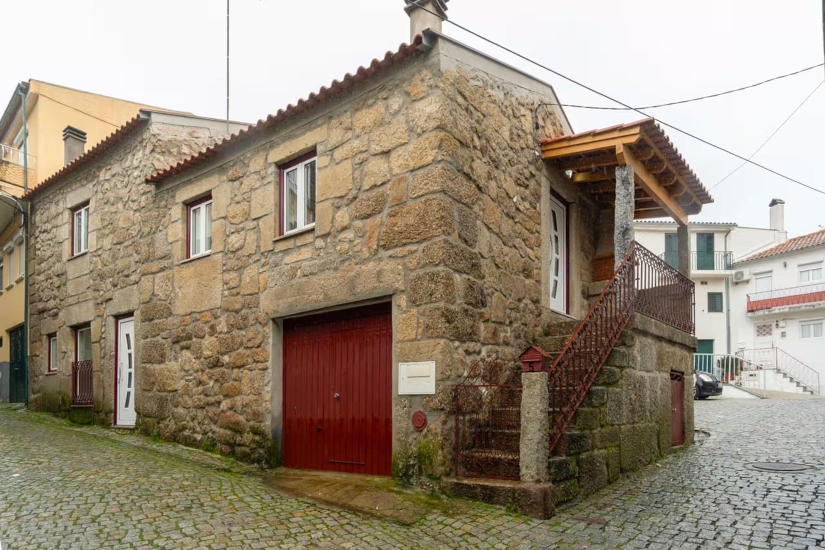 Ein Steinhaus mit roter Tür und einer kleinen Treppe, die zu einer Veranda führt.