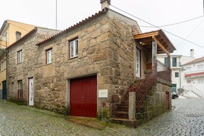 Ein Steinhaus mit roter Tür und einer kleinen Treppe, die zu einer Veranda führt.