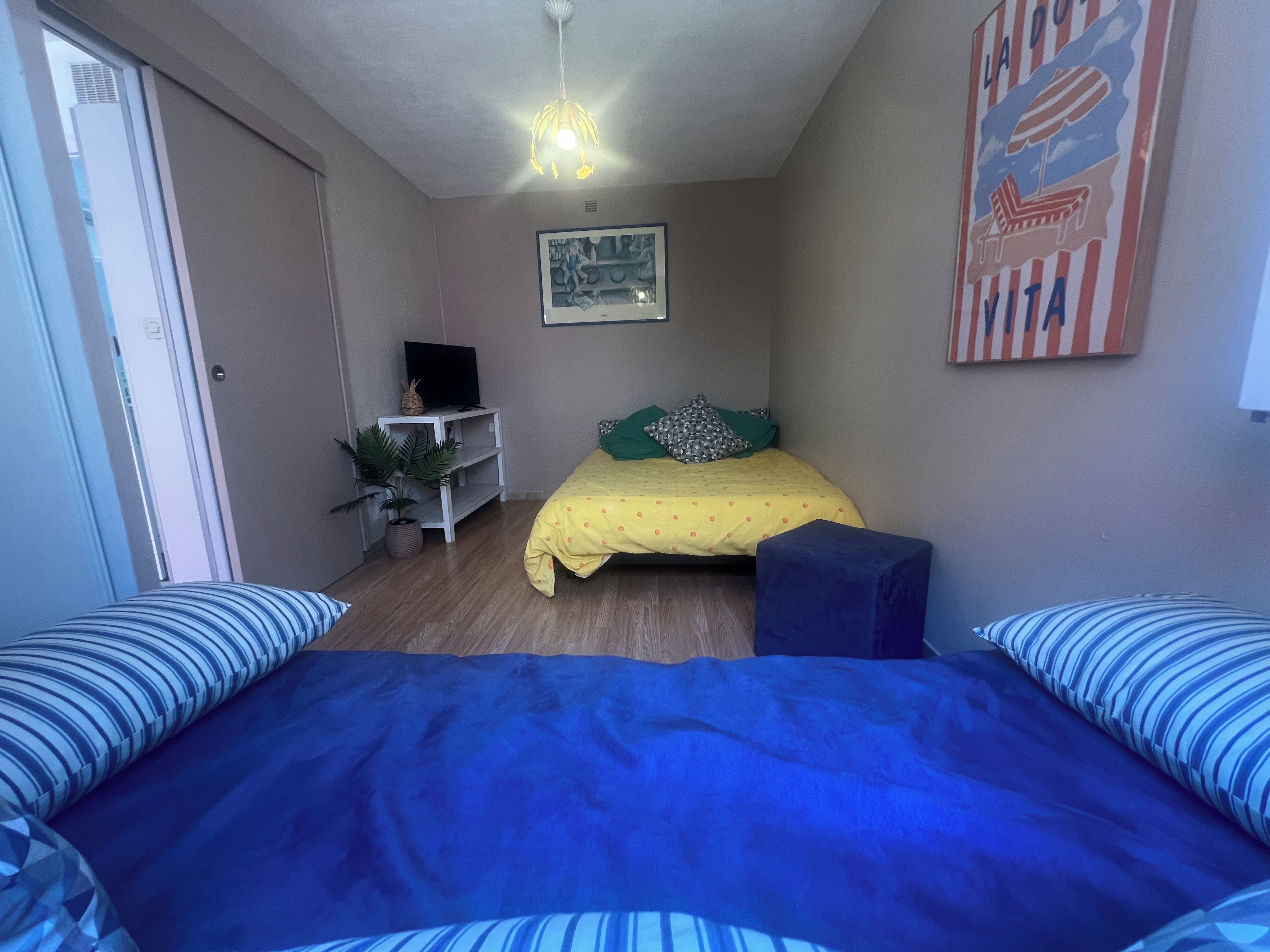 Een slaapkamer met een bed, een bureau, een televisie en een decoratie aan de muur.