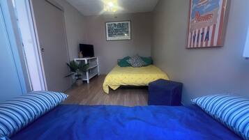 Een slaapkamer met een bed, een bureau, een televisie en een decoratie aan de muur.