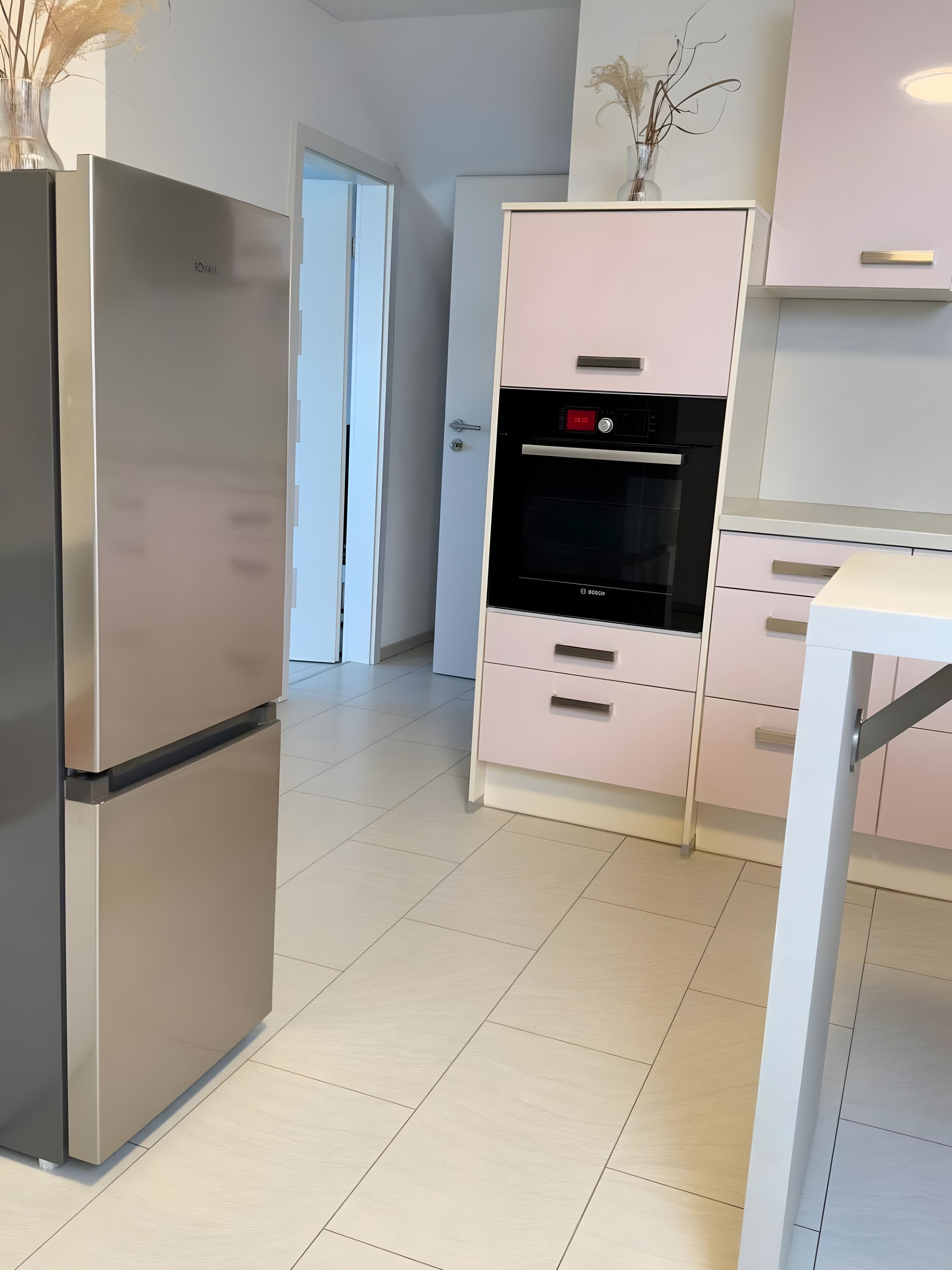 Eine moderne Küche mit einem Edelstahl-Kühlschrank, einem Einbauofen und weißen Schränken.