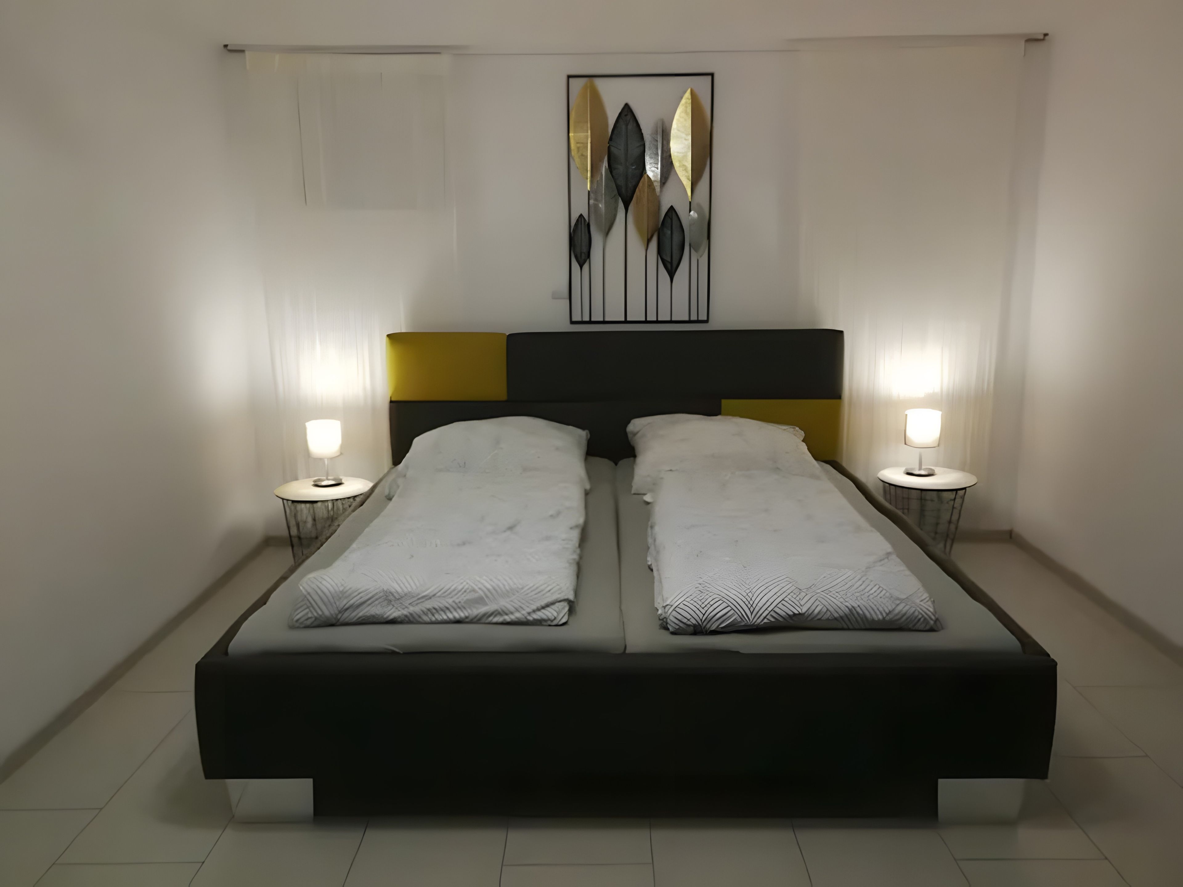 Ein Doppelbett mit schwarzem Kopfteil und zwei Nachttischen mit Lampen.