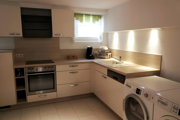 A compact kitchen with a built-in oven, a dishwasher, and a washing machine. - Apartment 'Stay & Relax – Wellness' with Private Terrace, Private Garden and Wi-Fi (Rottweil)