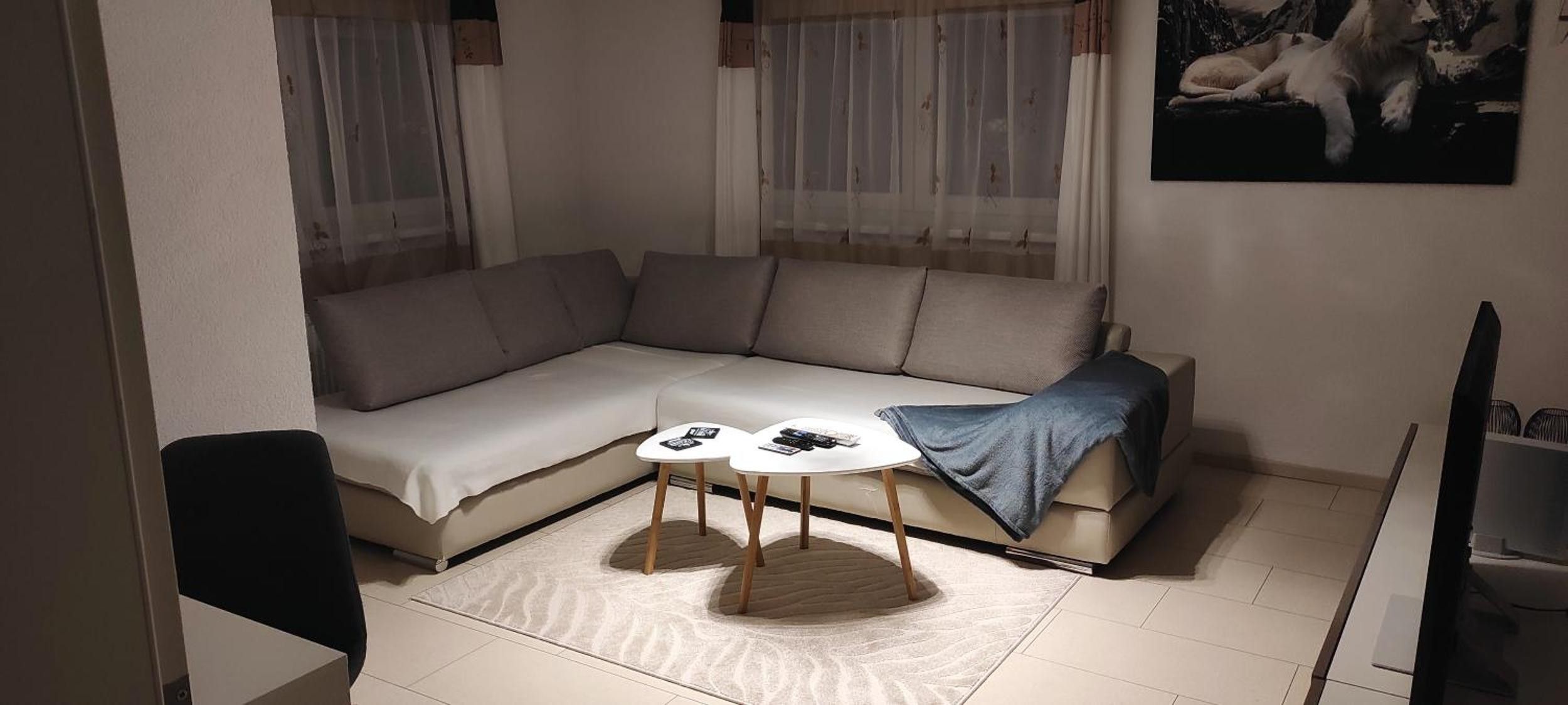 Ein modernes Wohnzimmer mit einer Eckcouch, einem kleinen runden Tisch und einem Bild an der Wand.