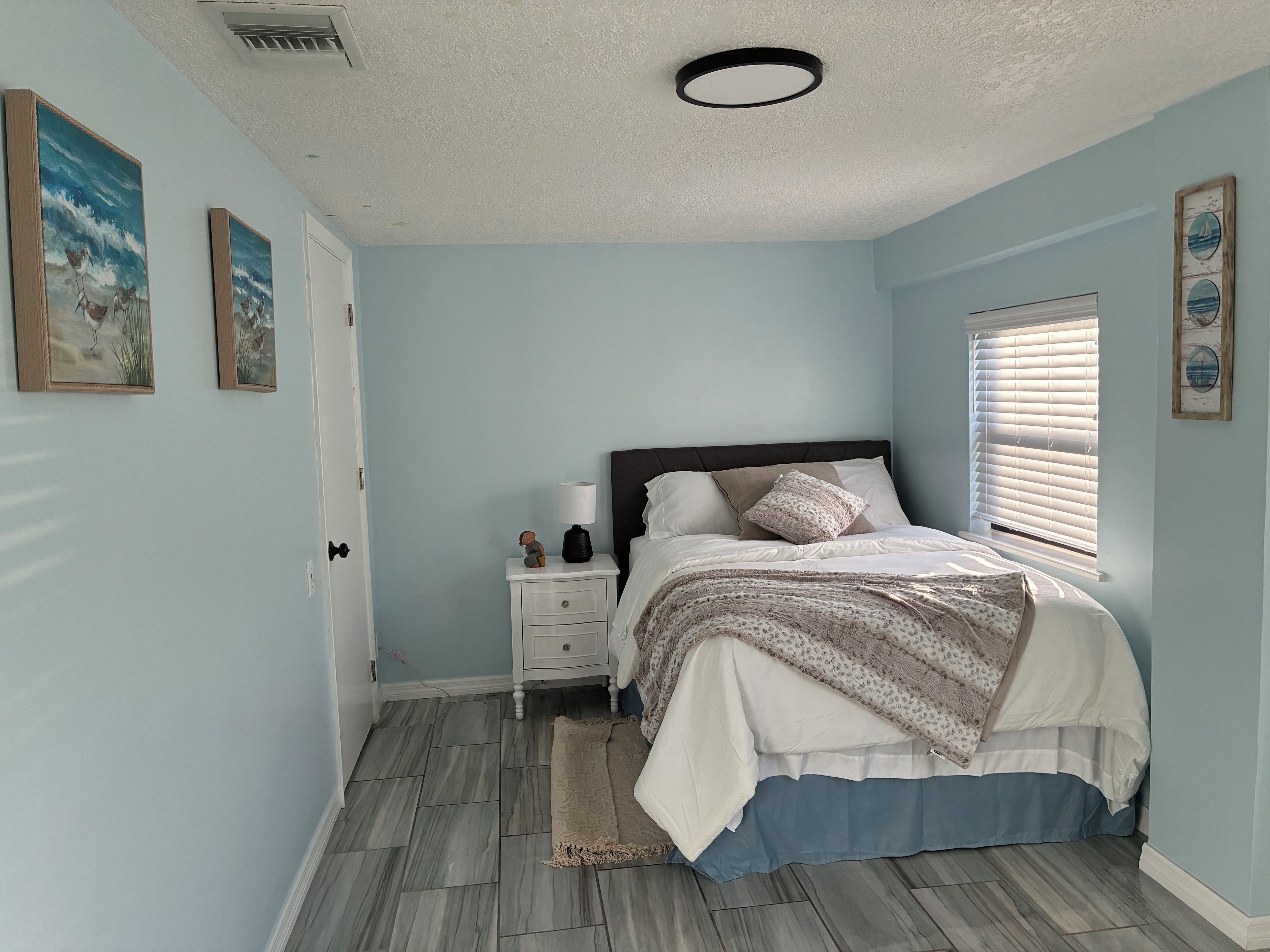 Un dormitorio con cama, mesita de noche y decoración en la pared.