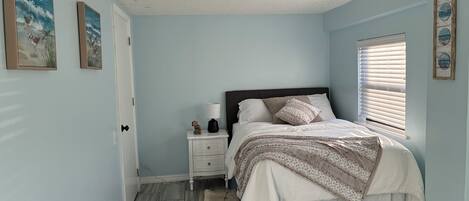 Un dormitorio con cama, mesita de noche y decoración en la pared.
