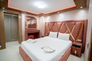 Habitació d'hotel amb un llit gran, una taula de nit, un armari i un mirall.