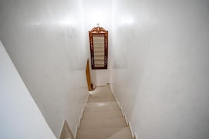 A narrow, white-walled stairway leading to a door with a wooden frame and glass panels. - New Listing (Marrakech)
