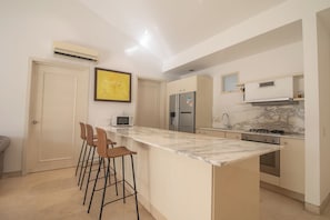 A modern kitchen with a marble countertop, stainless steel appliances, and a bar stool area. - Charming 3 Bedroom in the Old City (Cartagena de Indias)
