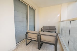 A balcony with two chairs and a sofa, a sliding glass door, and a tiled floor. - Charming 3 Bedroom in the Old City (Cartagena de Indias)