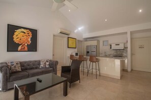 A living room with a sofa, a glass coffee table, and a painting on the wall. - Charming 3 Bedroom in the Old City (Cartagena de Indias)