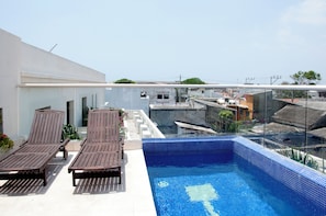 A rooftop swimming pool with lounge chairs and a view of the cityscape. - Charming 3 Bedroom in the Old City (Cartagena de Indias)