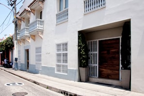 A building with a white facade, multiple balconies, and a large wooden door. - Charming 3 Bedroom in the Old City (Cartagena de Indias)