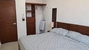A bedroom with a bed, a wardrobe, a mirror, and a chair. - New Listing (Progreso)