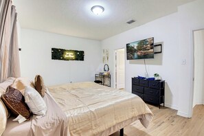 A bedroom with a bed, a dresser, a television, and a decorative wall piece. - Game Night HQ! Arcade, Pool Table & 5BR (Seguin)
