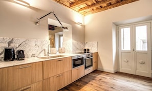 A kitchen with marble backsplash, wooden cabinets, a built-in oven, and a coffee maker. - DESIGNER ROMAN APARTMENT WITH TWO ENSUITE BEDROOMS AND A SPA-LIKE TOUCH (Roma)