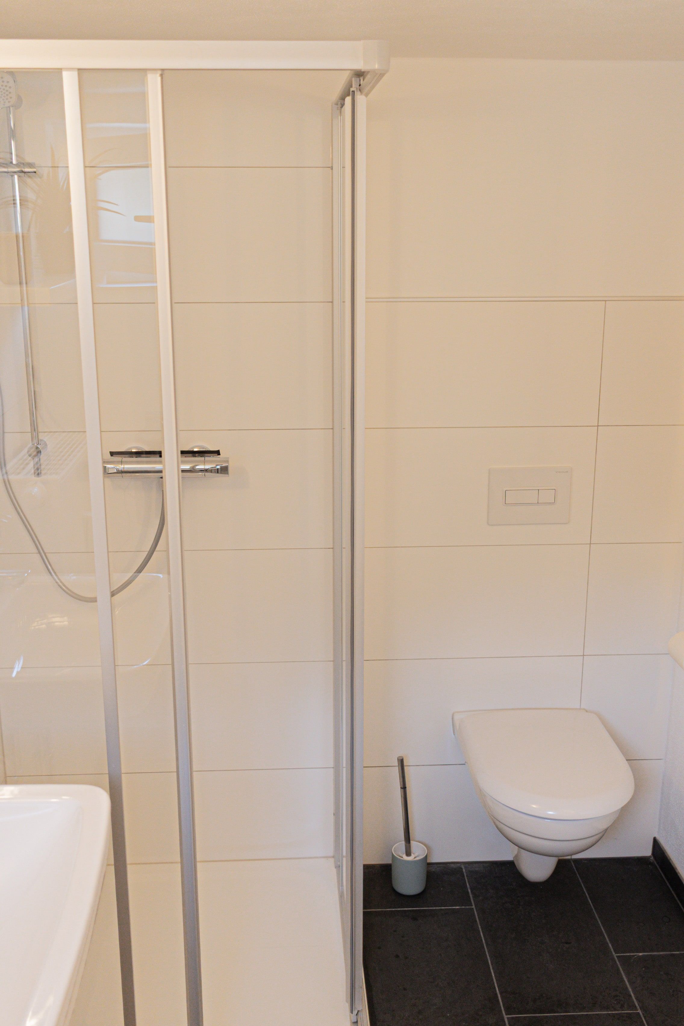 Een badkamer met douchecabine, toilet en een bidet.