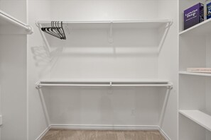 Un dressing avec deux étagères et une tringle à vêtements.