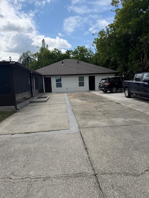 A building with a garage, a driveway, and a black pickup truck parked on the right. - Relax & Unwind – Private Pool and Family Comfort (Pinellas Park)