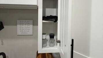 A kitchen with a white cabinet, a wooden round base, a sink, and a note on the wall.