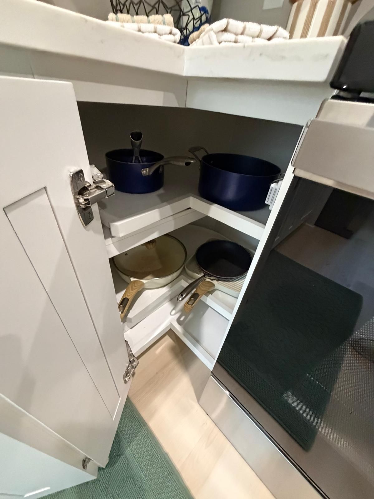 A kitchen with white cabinets, a microwave, and various pots and pans.