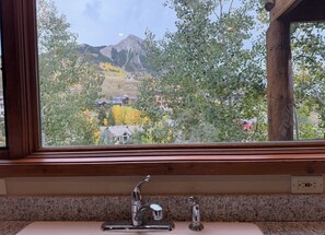 Eine Küche mit einer Granitarbeitsplatte, einem Edelstahlarmaturen und einem Fenster mit Blick auf eine gebirgige Landschaft.