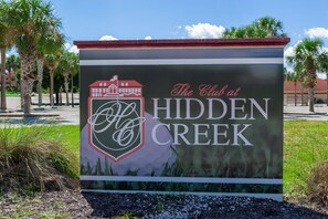Segnale per 'The Club at Hidden Creek' con un logo raffigurante un edificio e una forma a onda.