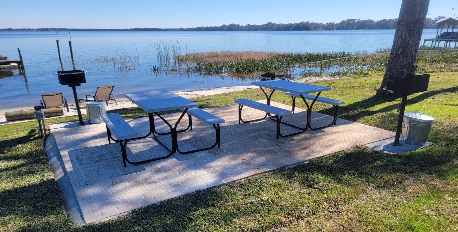 A picnic area with tables and chairs by a lake.